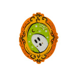 Die-cut guest napkin shaped like an ornate gold frame holding a white ghost on a green ground.