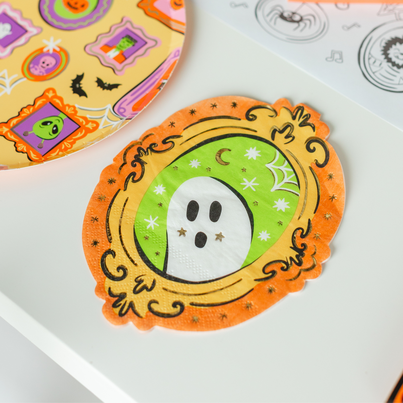 Ghost-frame guest napkin on a table with framed-monster print plates and a coloring placemat.
