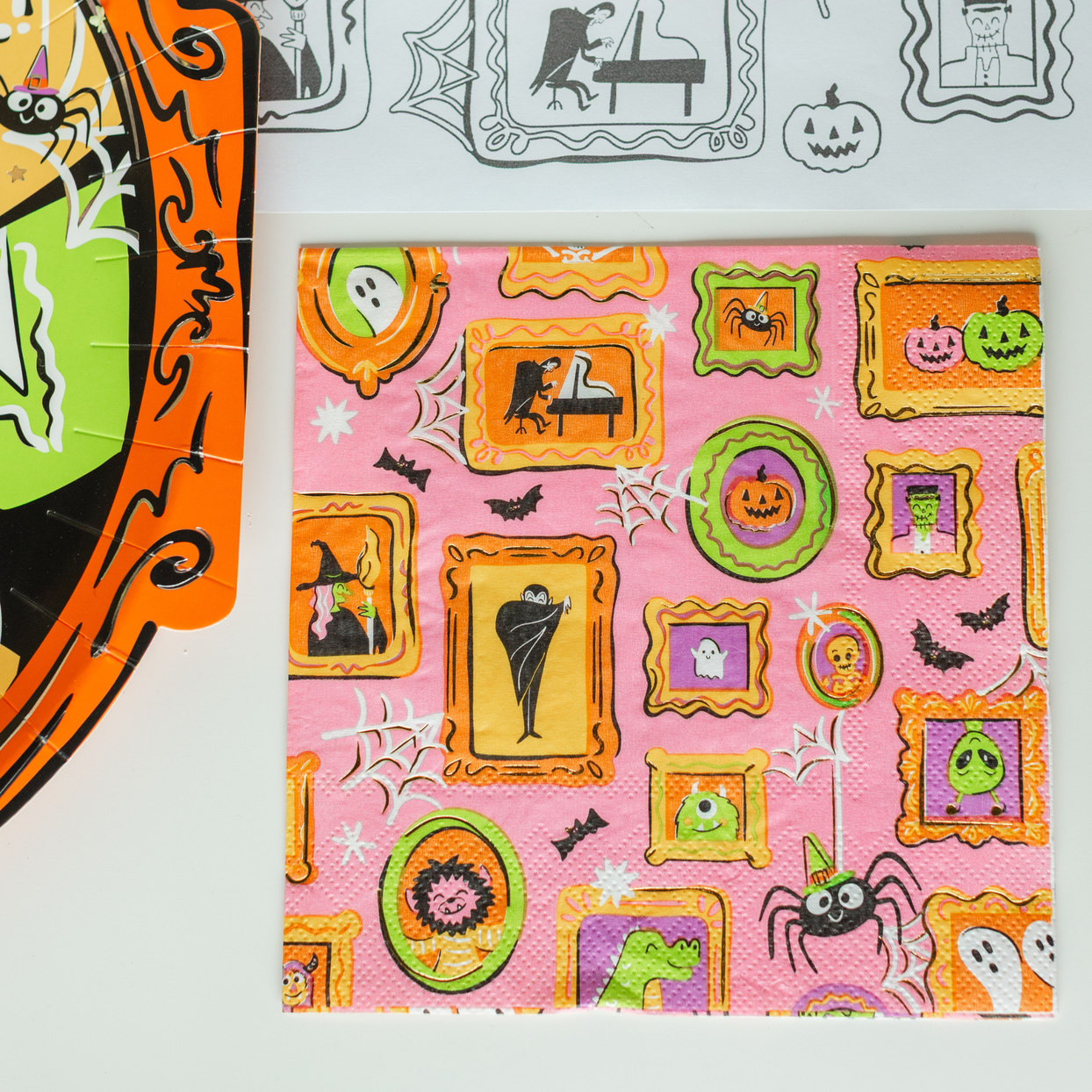 Monster Mash pink frame-print napkin beside an orange frame-print plate.