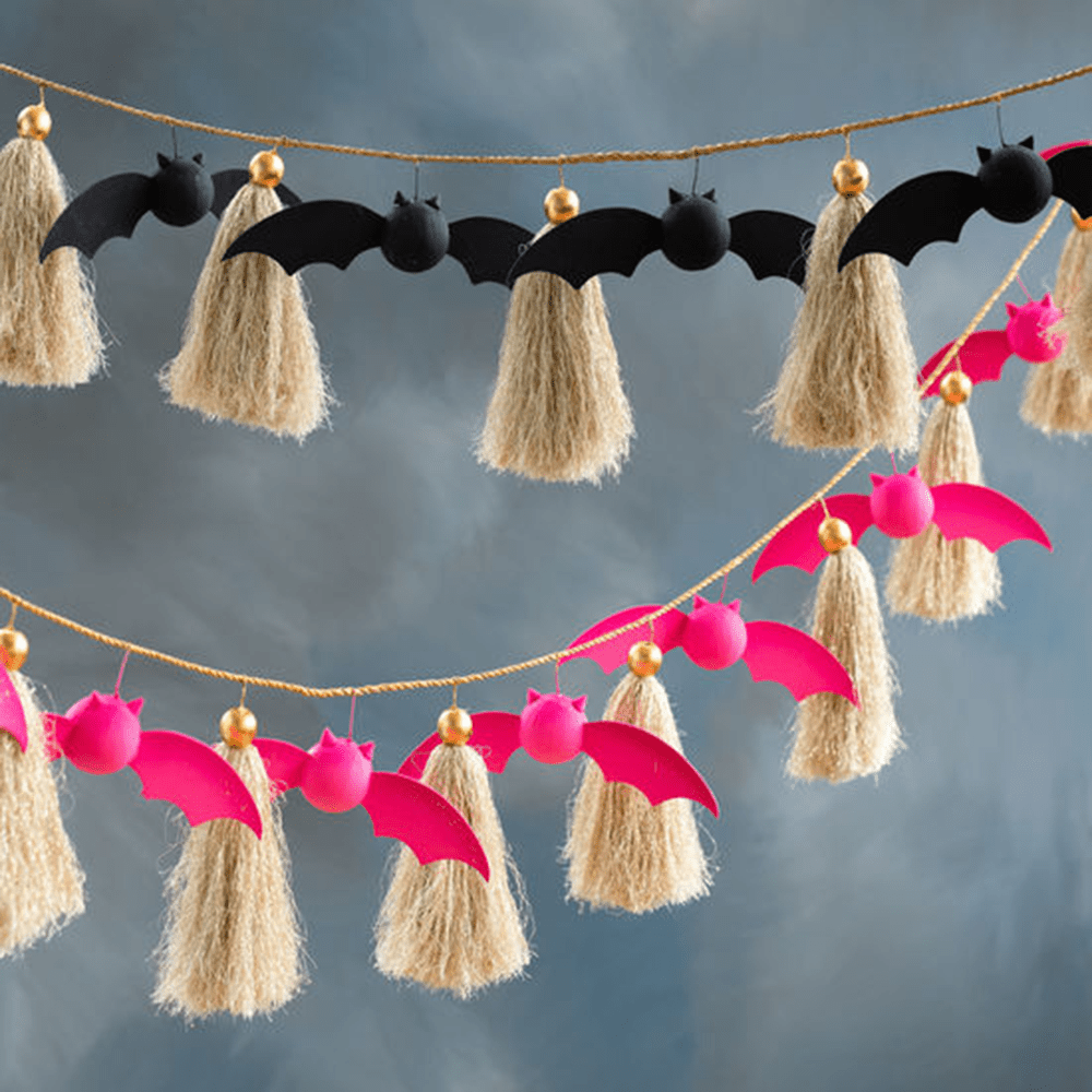 Black and hot-pink papier-mache bat garlands with tassels, shown side by side.